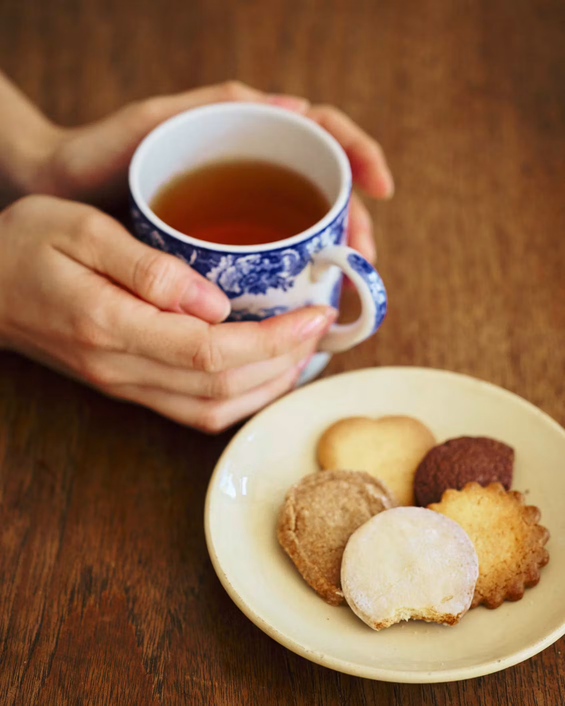 紅茶が入ったカップを手に持ち、サブレと一緒に楽しむ様子